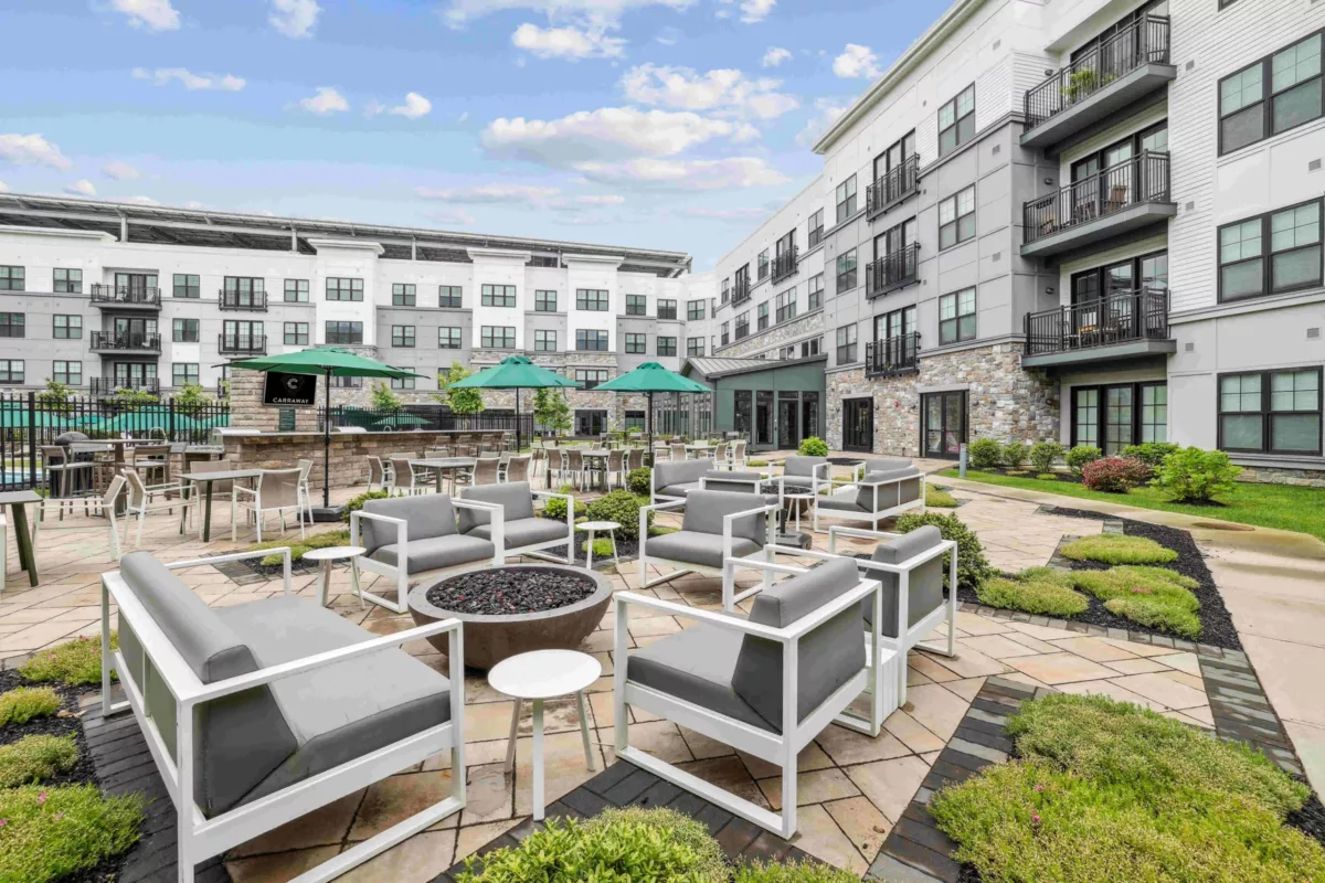 Outdoor lounge with firepit, gray cushioned seating, and green umbrellas.