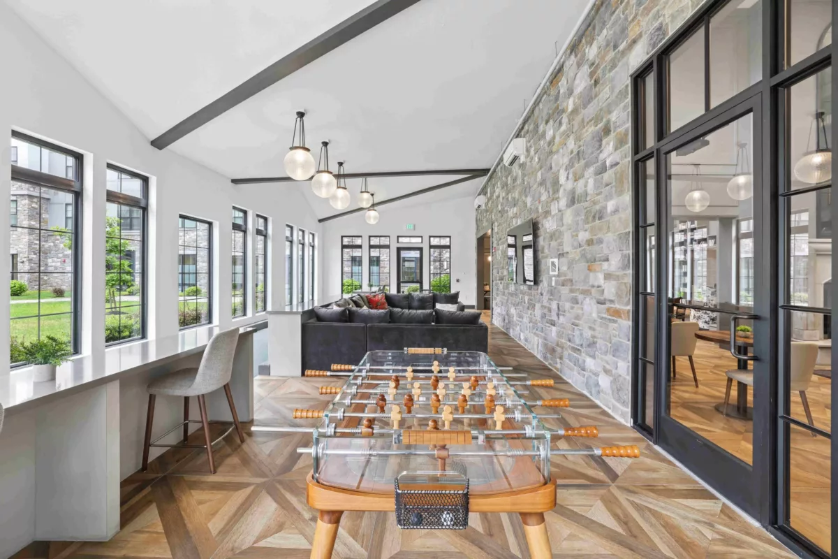 Lounge with foosball table, gray sectional sofa, and stone accent wall.
