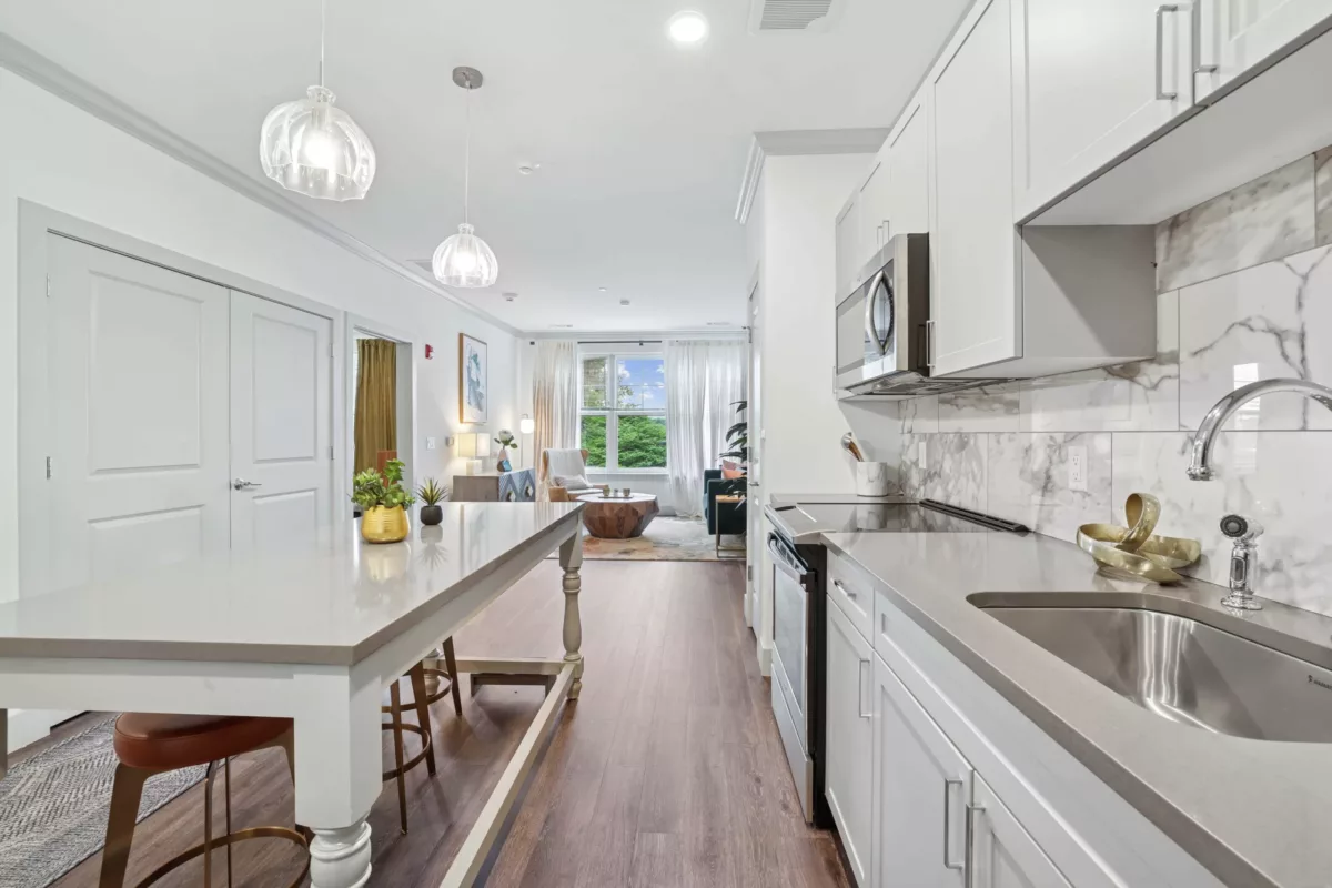 Modern kitchen with white cabinets, stone countertops, and pendant lighting.