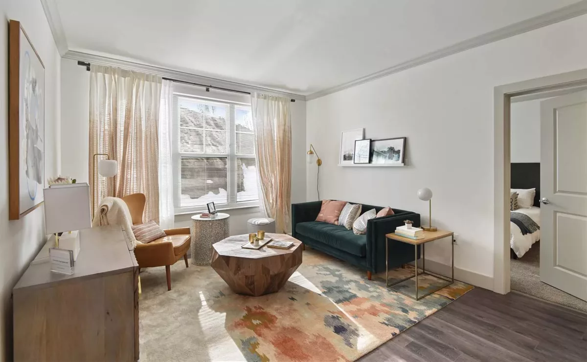 Living room at Carraway with green couch and large window for natural light